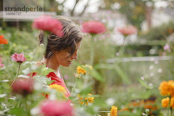 Eine Frau steht halb versteckt in einem schönen Beet mit Wildblumen im Sommer