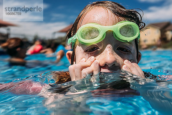 Kleines Kind wischt sich an einem Sommertag im Schwimmbad das Gesicht ab