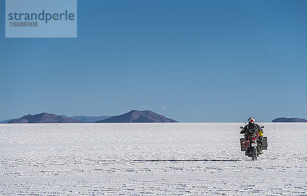 Ein Mann fährt mit seinem Reisemotorrad auf den Salinen von Uyuni in Bolivien