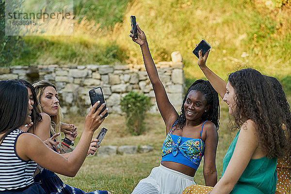 Gruppe von Freundinnen in einem Park  die auf ihr Smartphone schauen