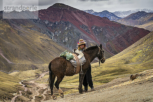 Reiter mit Pferd auf dem Rainbow Mountain Trail mit hohen Andenbergen im Hintergrund  Pitumarca  Peru