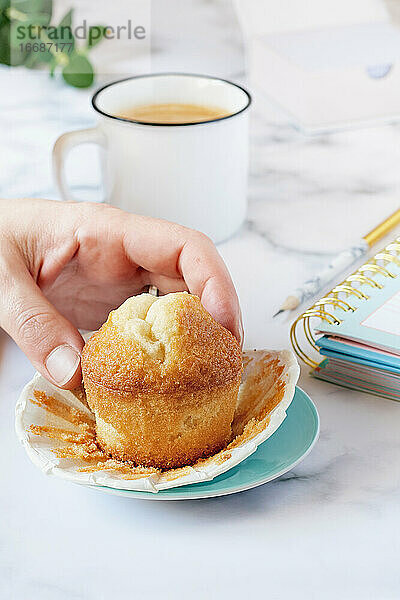 Die Hand einer Frau greift nach einem selbstgebackenen Muffin.