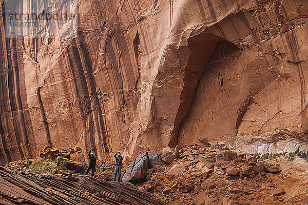 Menschen unter hohen Sandstein-Canyonwänden in der Nähe des Escalante River  Utah