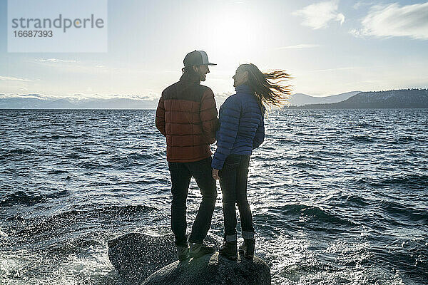 Junges verliebtes Paar steht auf einem Felsen im Lake Tahoe im Winter