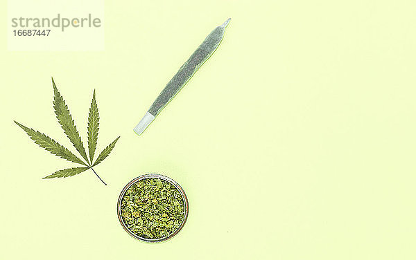 Big Marihuana Joint  Grinder voll von gehackten Gras und Blatt auf gelbem Hintergrund mit Kopie Raum rechts.