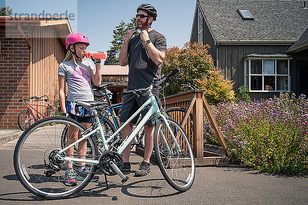 Vater und Tochter setzen Fahrradhelme auf und bereiten sich auf das Fahrradfahren vor