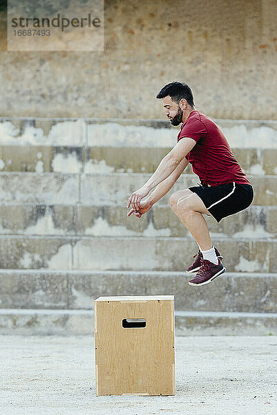 Ein Mann übt Crossfit und springt in eine plyometrische Box.