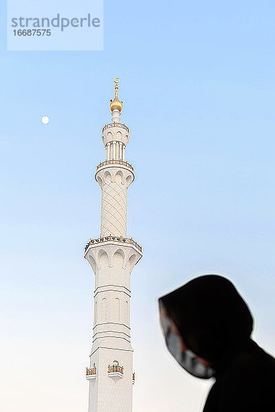 Silhouette einer muslimischen Frau  bedeckt mit einer schwarzen Abaya in einer großen Moschee