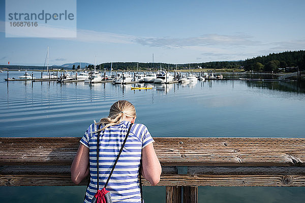Junges Mädchen schaut von einem Dock im Hafen von Lopez Island in WA