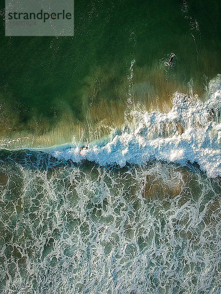 Luftaufnahme von Surfern und einer großen Welle im Ozean. Ansicht von oben