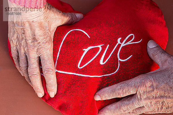 Älteres Paar hält Herz mit Liebeswort