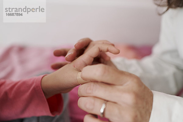 Detail der heilenden Hand eines Arztes mit einem Pflaster auf der Hand eines Mädchens