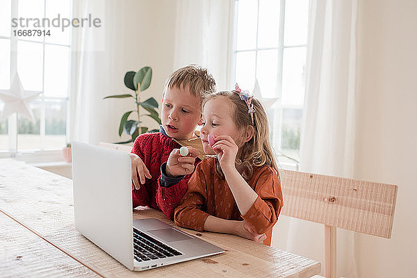 Kinder zeigen ihrer Familie bei einem Videoanruf während der Isolation Schokolade