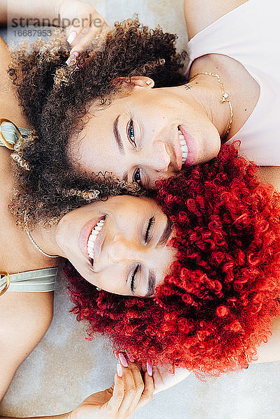 Zenithales Porträt zweier lateinamerikanischer Frauen mit Afro-Haar auf dem Boden.