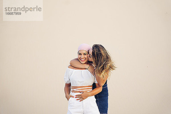Junge Frau mit rosa Kopftuch kämpft zusammen mit ihrer Freundin gegen den Krebs.