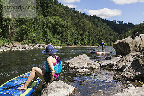 Ein junges Paar genießt den Fluss auf ihren SUPs in Oregon.