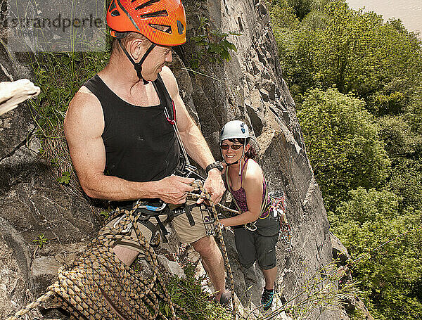 Paar klettert an steiler Felswand in Südwales