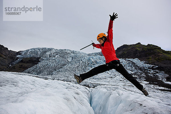 Frau springt über Gletscher auf dem Sólheimajökull-Gletscher in Island