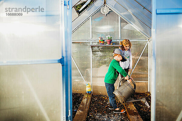 Zwei junge Kinder kümmern sich um Pflanzen im Gewächshaus