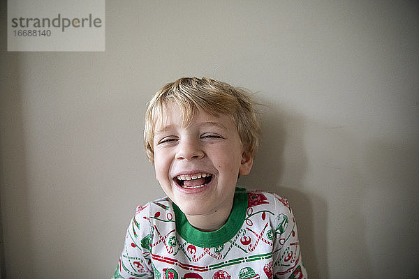 Close Up Portrait eines lachenden Jungen in einem roten und grünen Weihnachtspyjama