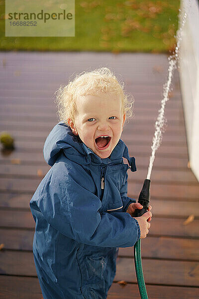 Junge spielt mit dem Wasser und lacht