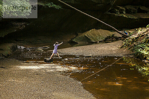 Zwei Kinder spielen im Sommer an einem Bach in einer Sandsteinschlucht