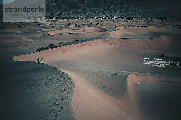 Zwei Personen wandern auf dem Kamm einer Sanddüne im Death Valley National Park