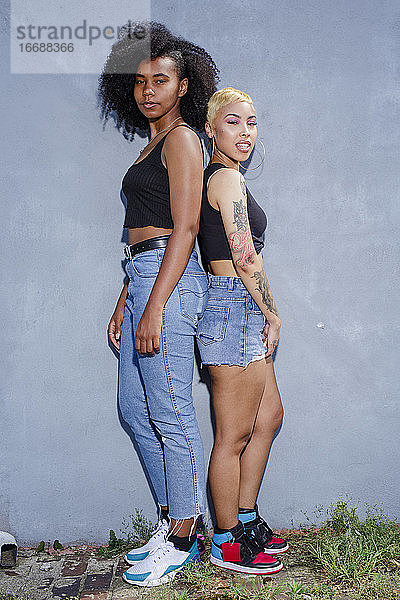 Zwei identisch gekleidete junge Frauen stehen Rücken an Rücken zusammen