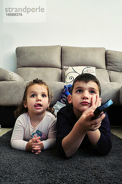 Geschwister  die zu Hause einen Film ansehen und dabei Popcorn essen