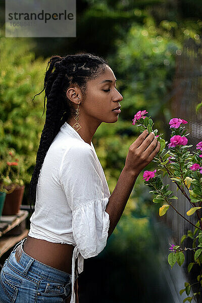 Junge schwarze Frau riecht an Blumen