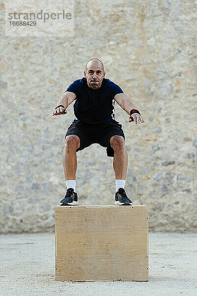 Ein Mann übt Crossfit und springt in eine plyometrische Box.