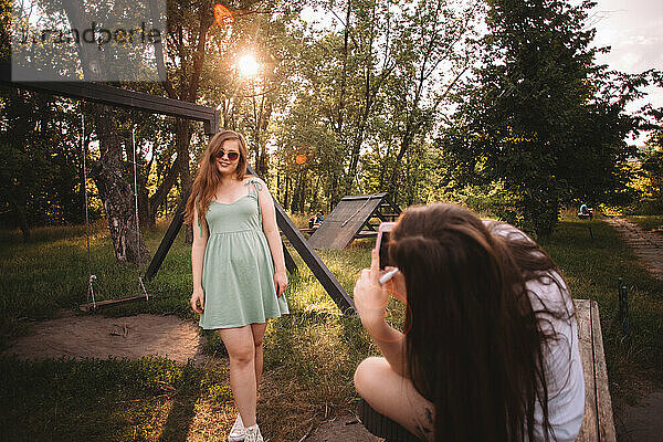 Junge Frau fotografiert ihre Freundin im Sommer im Park