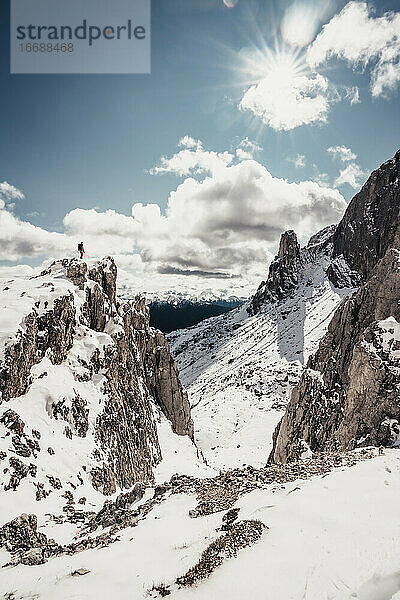 Bergsteigerin steht auf dem Gipfel eines verschneiten Berges und genießt die Aussicht