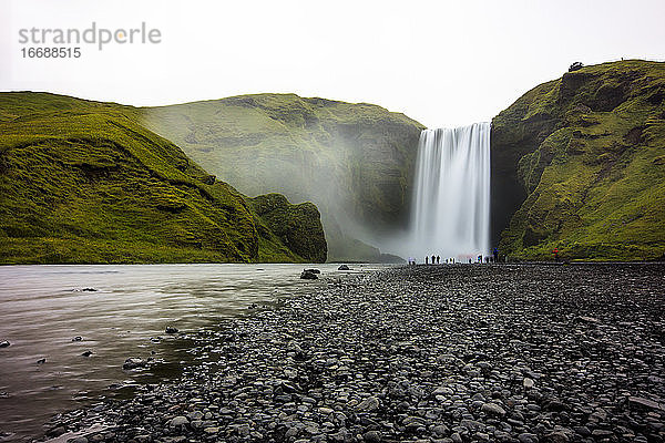 Wanderer unter dem berühmten isländischen Wasserfall Skogafoss.