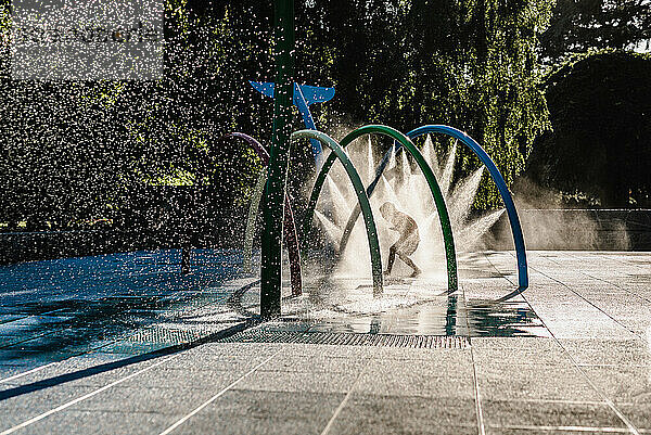 Silhouette eines Kindes  das im Park durchs Wasser läuft