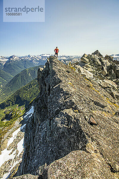Trailrunner steht auf einem Berggipfel  am Rande einer Klippe.