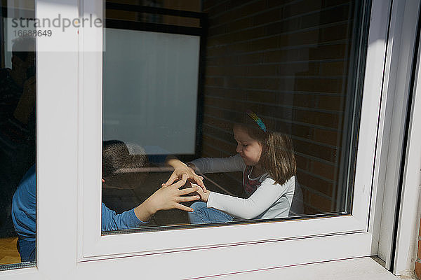 Kinder spielen hinter dem Fenster zu Hause