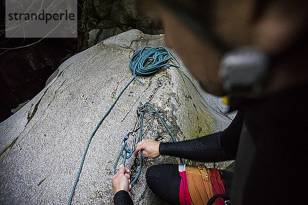 Blick von oben auf einen Kletterer  der eine Abseilstation in einer Schlucht einrichtet.