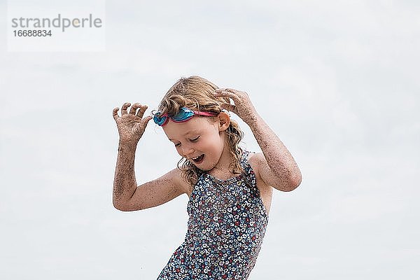 Mädchen mit Taucherbrille tanzt am Strand und hat Spaß im Sommer