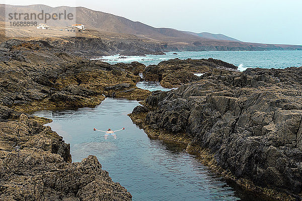 Mann beim Schwimmen und Entspannen im natürlichen Meeresschwimmbad auf der Insel Fuerteventura.