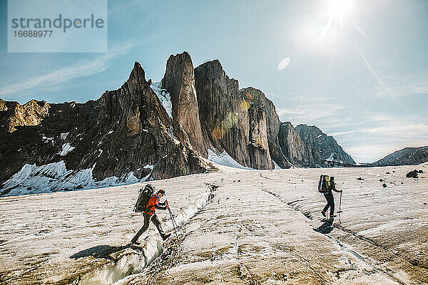 Bergsteiger durchqueren an einem sonnigen Tag eine Gletscherspalte auf Baffin Island.