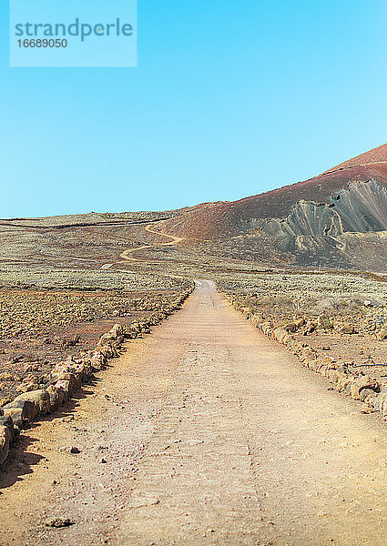 Wüstenlandschaft mit einem Fleck zwischen den Bergen an einem sonnigen Tag. Weg zum Vulkan Calderón Hondo auf Fuerteventura.