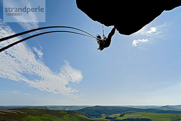 Frau beim Abseilen von einer Klippe bei den Windgather-Felsen im Peak District