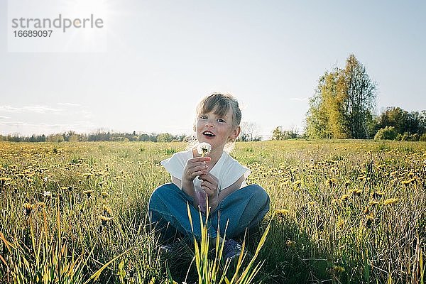junges Mädchen hält freudig eine Blume in einem Blumenfeld im Sommer