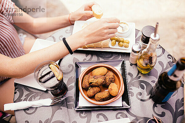 Frau isst typisch spanisches Essen. Kroketten  Oliven und Knoblauchsauce