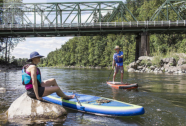 Ein junges Paar genießt den Fluss auf ihren SUPs in Oregon.