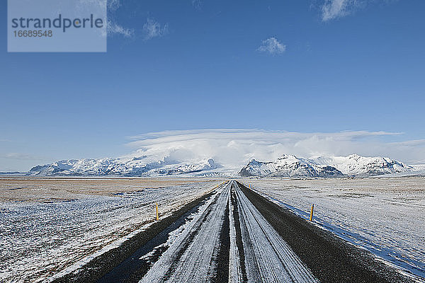 Gerade Straße  die zu einem majestätischen Berg in Island führt