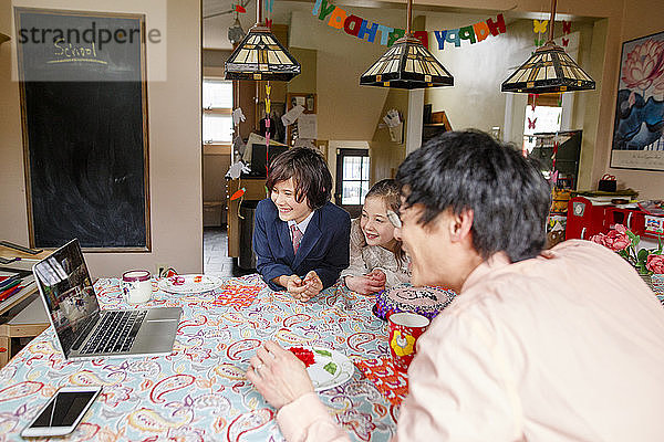 Eine glückliche Familie versammelt sich vor dem Computer zu einer Zoom-Geburtstagsfeier