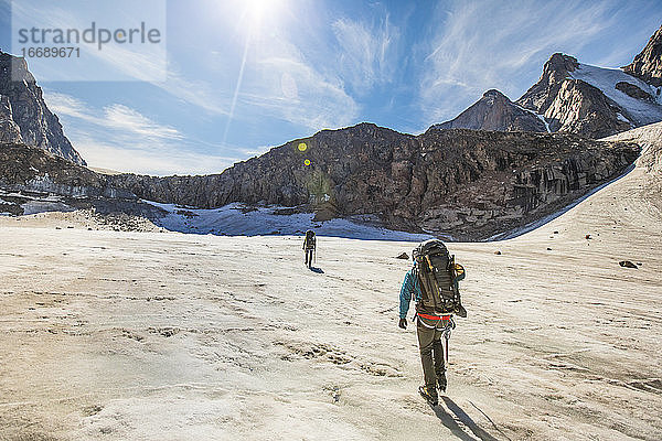 Bergsteiger nähern sich einer Stirnwand am Ende eines Gletschers im Gebirge.