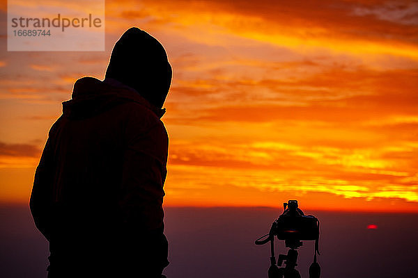 Silhouette eines Mannes  der ein Foto in den Bergen macht.